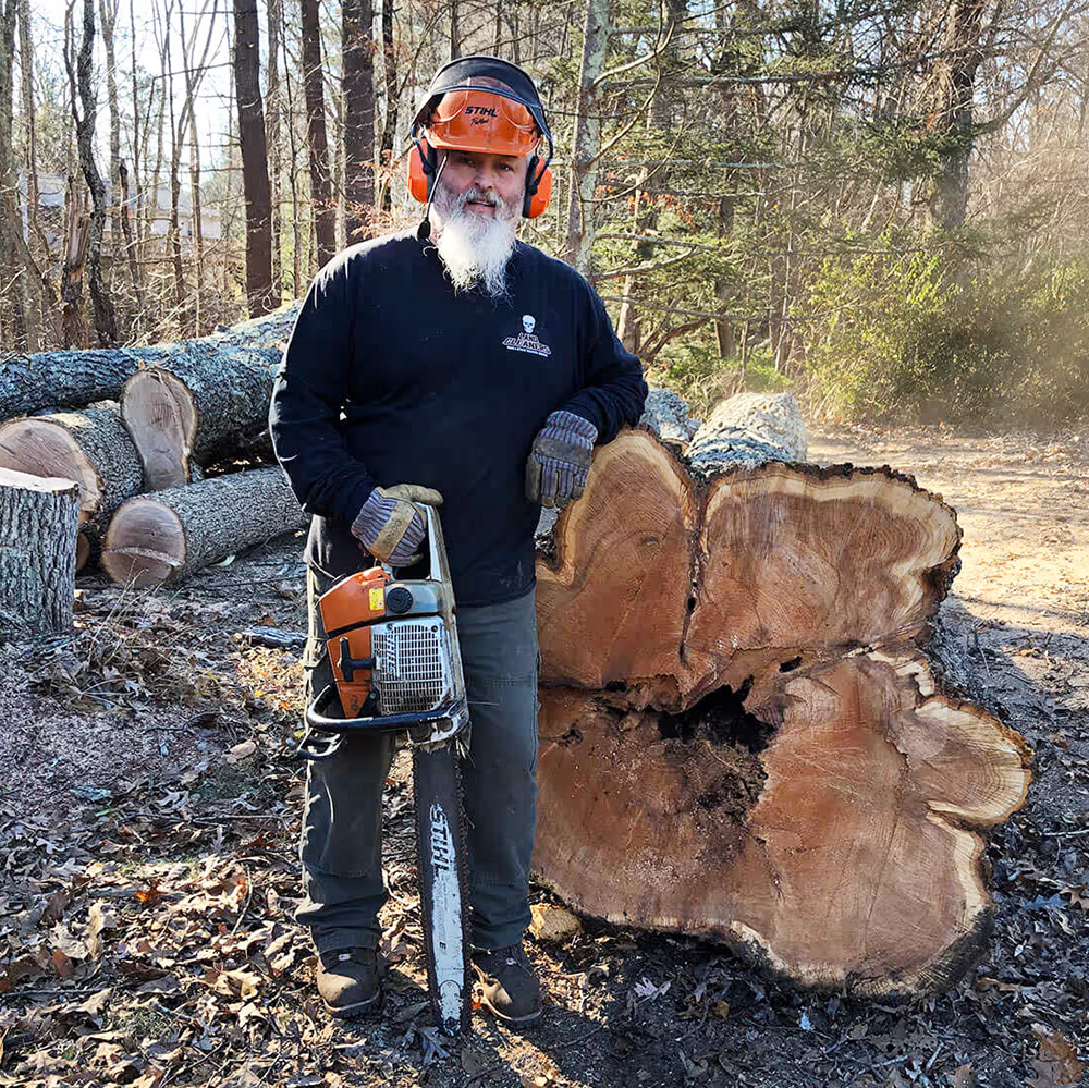 man with chain saw and fallen tree